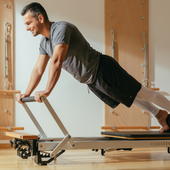 man doing a forward plank on a pilates machine