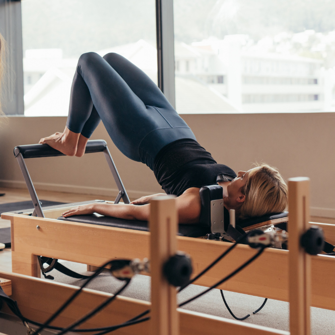 woman doing a front bridge exercise on a pilates machine