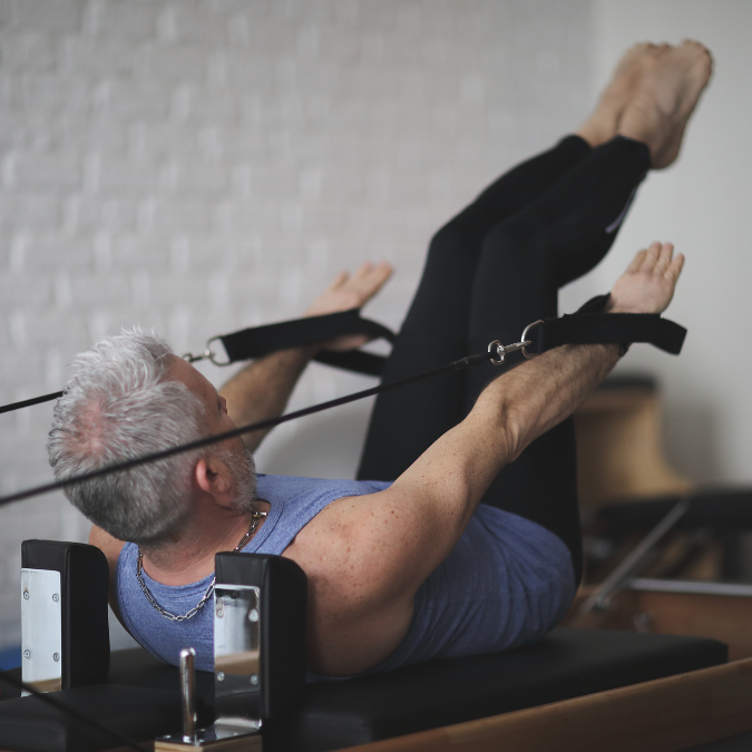 man lying down doing crunches on a pilates machine