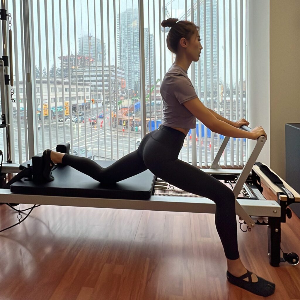 side view of a woman on pilates reformer in a deep lunge
