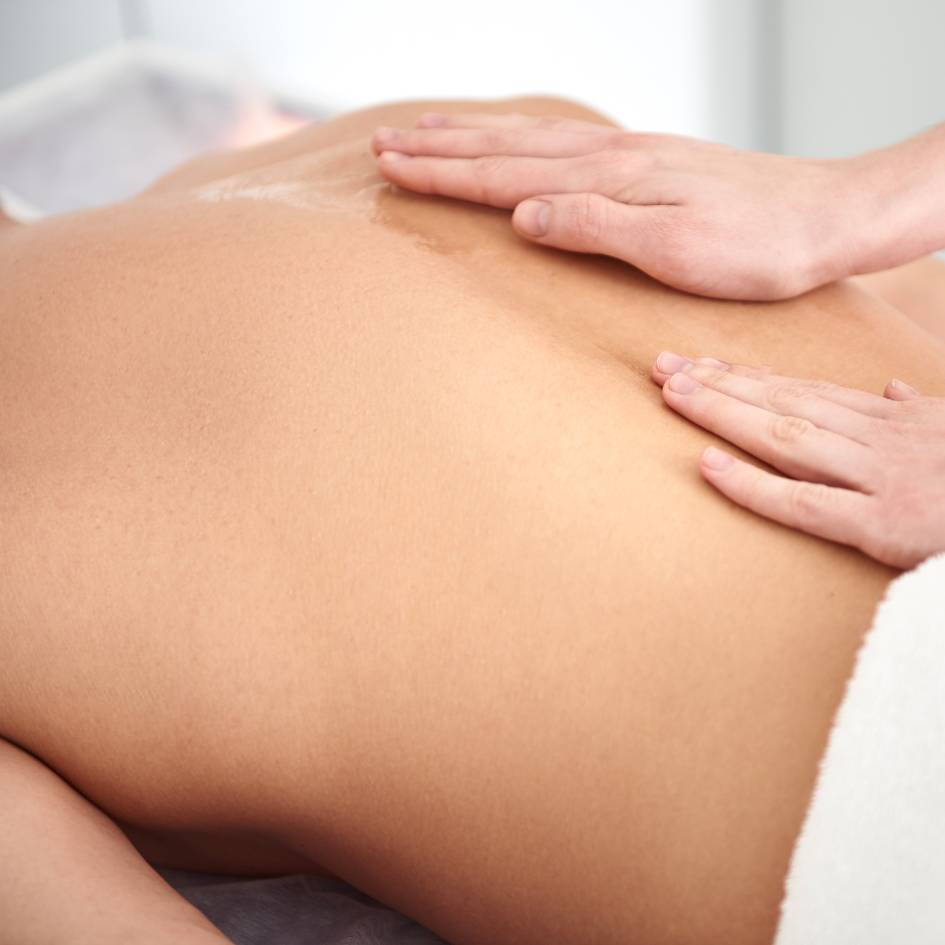 A close-up photo of a therapist's hands gently pressing on the upper back of a client during a Fascial Stretch Therapy session in Burnaby. The therapist is applying a soothing touch to help release tension in the fascia, promoting relaxation and enhancing the client's flexibility in the upper back region.