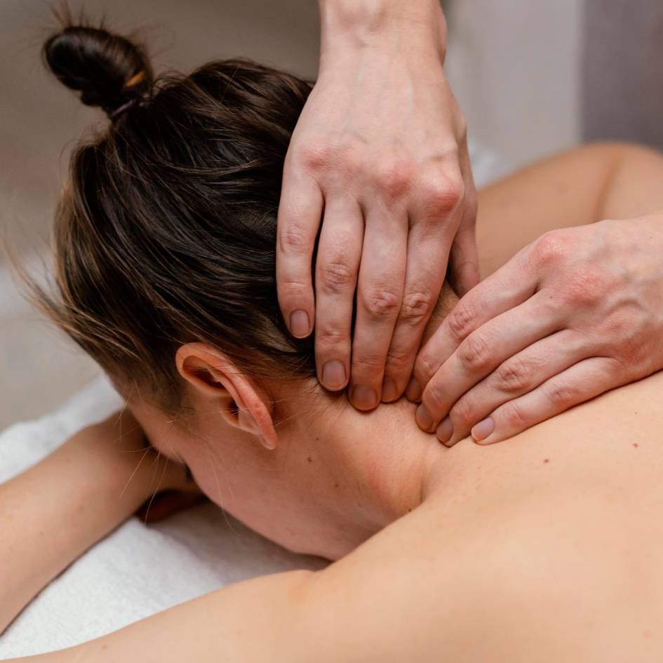 A detailed image showing a therapist’s hands performing a gentle fascia release on the upper neck of a female client lying face down during a Fascial Stretch Therapy session in Burnaby. The therapist uses precise, soothing pressure to help alleviate tension and enhance flexibility in the neck area, promoting deep relaxation.