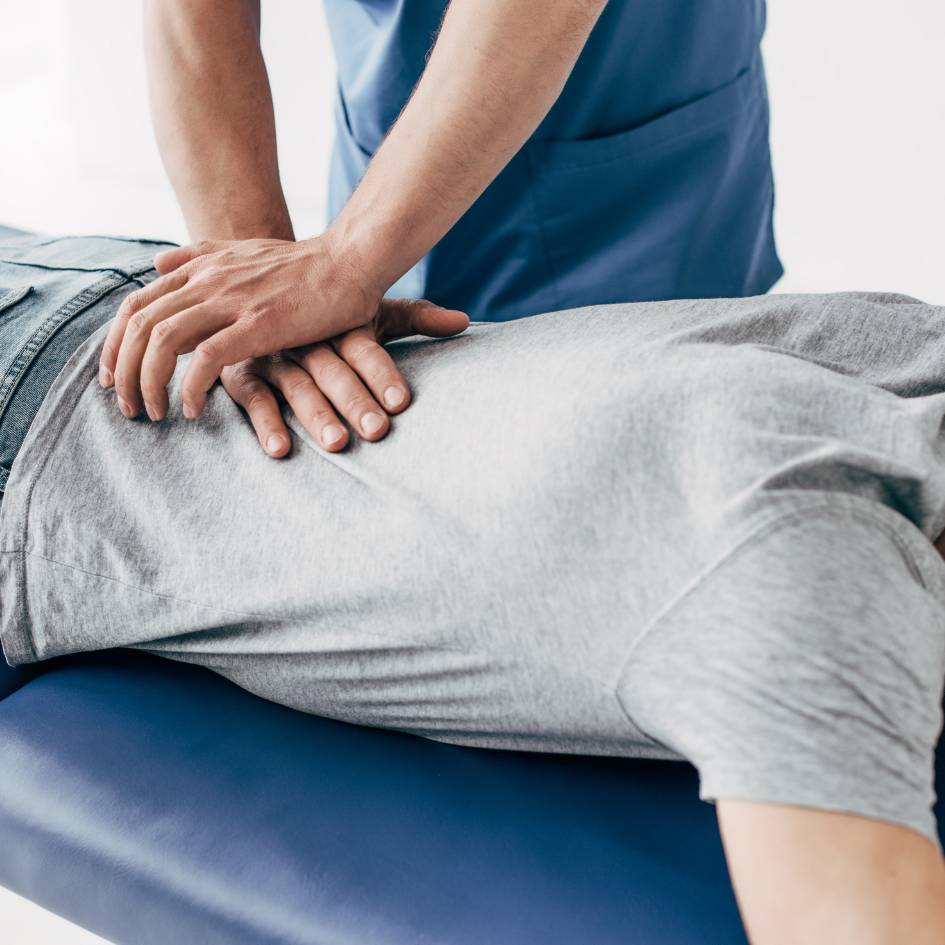 pilates instructor helping woman on pilates machine extend her leg in an exercise