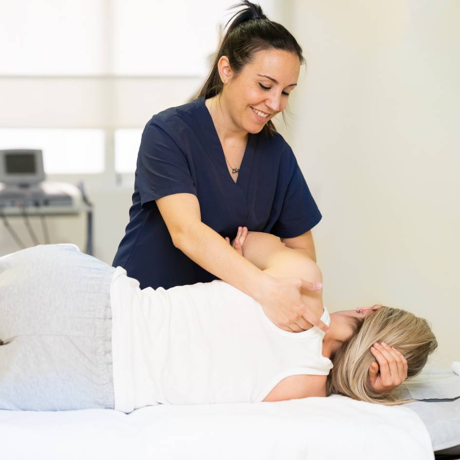 pilates instructor helping a woman side stretch her arms and core