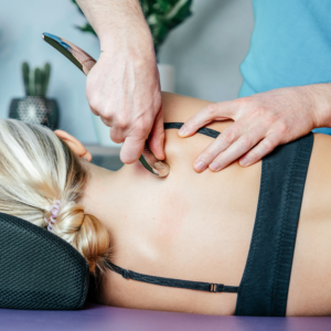 Registered Massage Therapist at Panda Clinic Metrotown performing therapeutic leg massage in a bright treatment room – RMT Burnaby service.